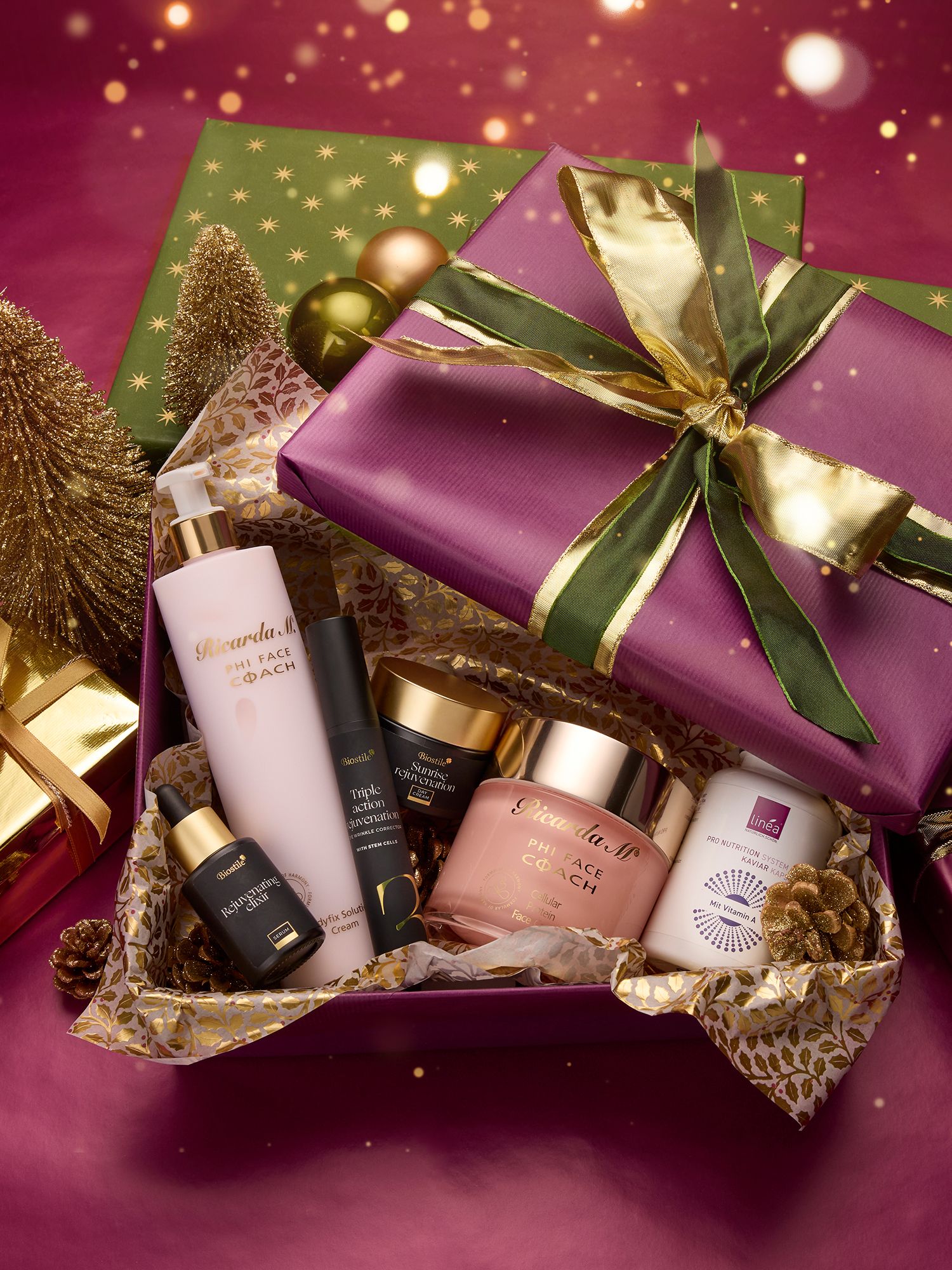 Beauty & Pflege Geschenkbox mit gold-grünem Band, gefüllt mit Kosmetikprodukten, darunter Flaschen und Tiegel, umgeben von goldenen Weihnachtsdekorationen.