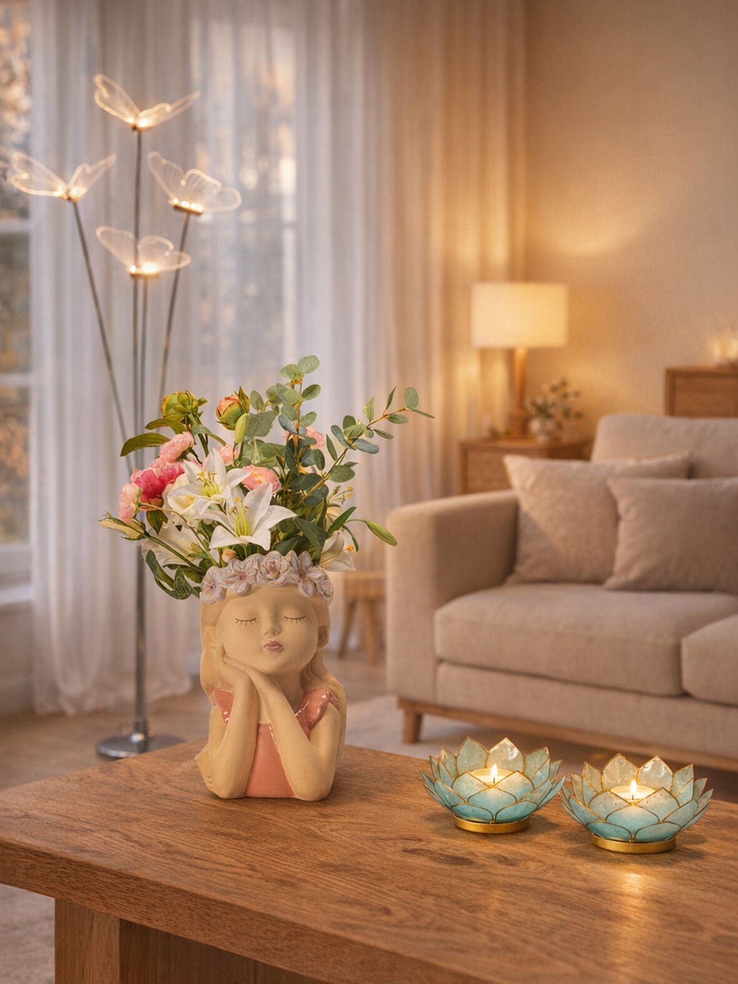 Wohnzimmer mit grauem Sofa, Stehlampe, Blumenstrauß in Vase auf Holztisch und zwei brennenden Kerzen in blauen Lotusförmigen Haltern