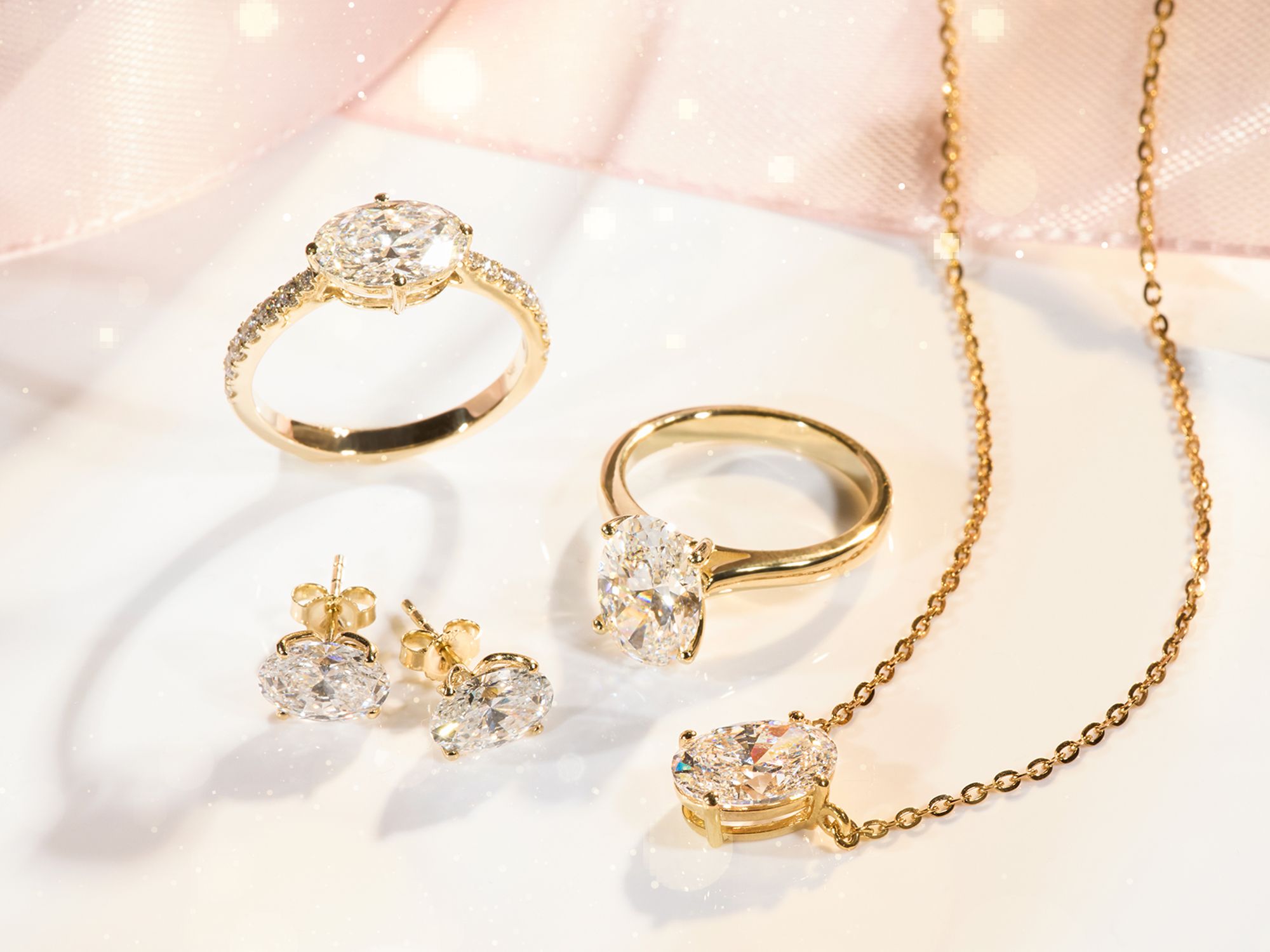 Goldener Schmuck bestehend aus zwei Ringen mit großen ovalen Steinen, einem Paar Ohrsteckern und einer Kette mit Anhänger