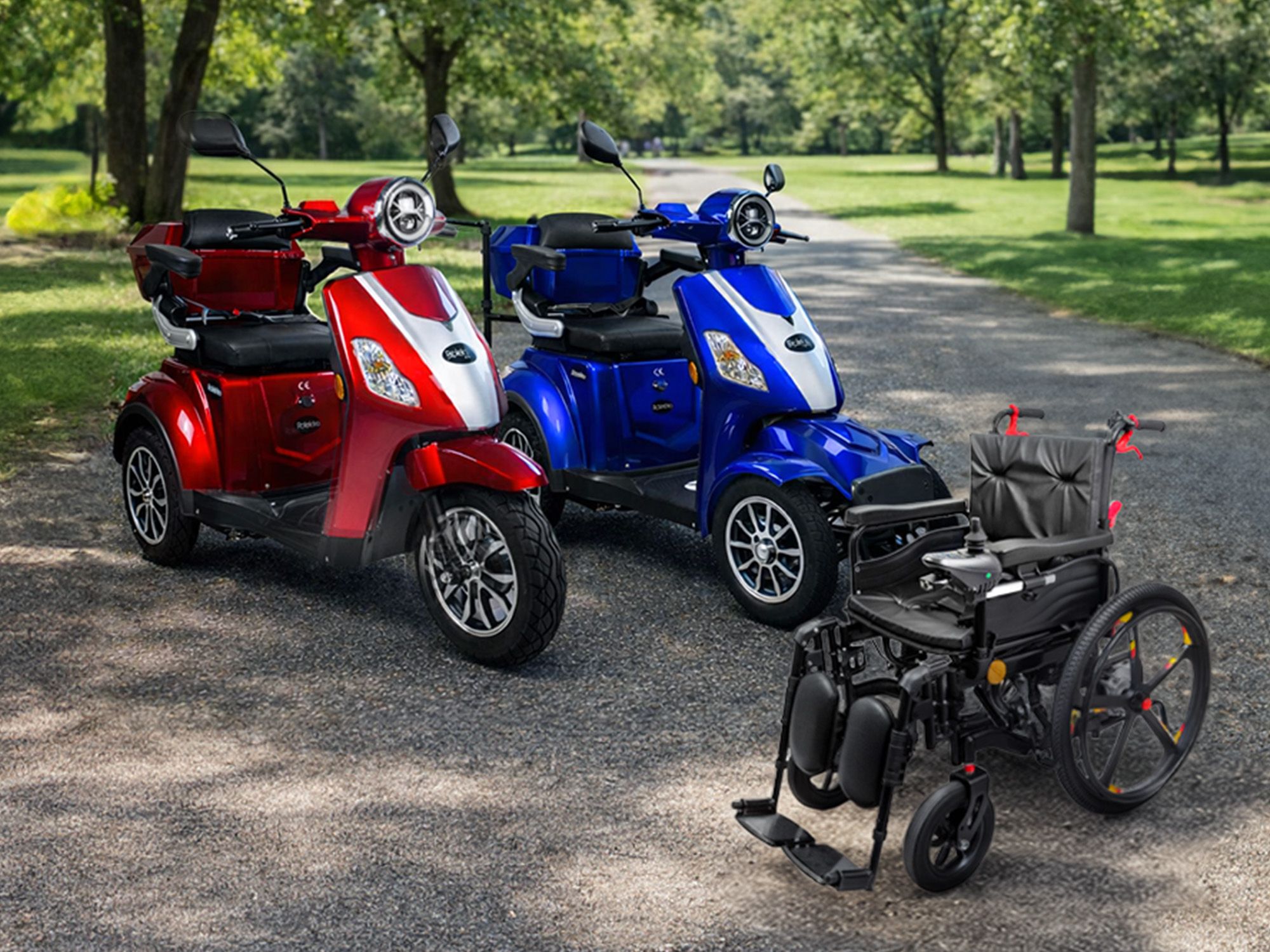 Zwei Elektromobile in Rot und Blau stehen nebeneinander auf einem Weg in einem Park, davor ein schwarzer elektrischer Rollstuhl